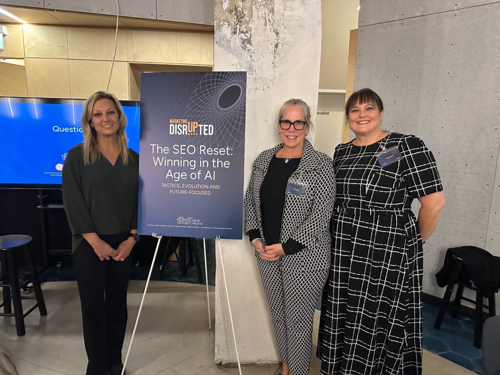 Alt text for web: Three 1905 New Media team members in front of “The SEO Reset: Winning in the Age of AI” sign for the Chicago Marketing Disrupted event.