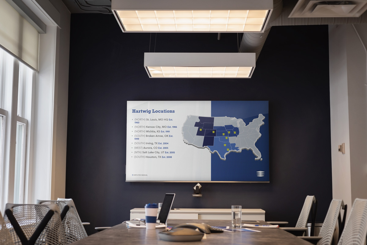 an office setting with a powerpoint screen showcasing the Hartwig locations around the U.S.