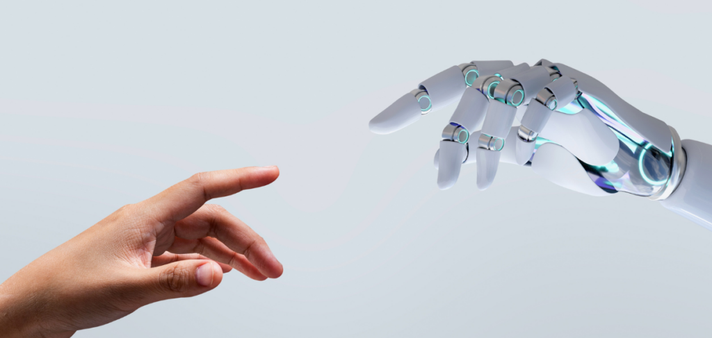 A human hand extends a finger outward from the left toward a white and chrome robotic hand reaching from the right against a solid light gray background.